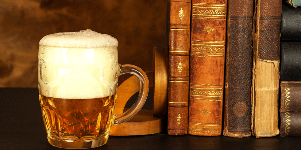 Glass of beer next to old books